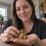Gold Laughing Buddha Statue with Ingot and Money Bag held by a woman at home