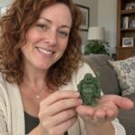Green Laughing Buddha Statue with Fan held by a woman at home