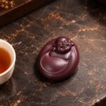 Mini purple clay Laughing Buddha resting flat, with a smiling face and rounded robe