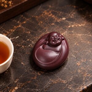 Mini purple clay Laughing Buddha resting flat, with a smiling face and rounded robe