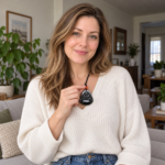 Woman holding the exact small ink jadeite Laughing Buddha pendant by its black cord in natural home light