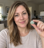 Woman holding a small pale green jadeite Laughing Buddha pendant in natural room lighting