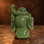 Source-supported rear studio photo of the green resin Laughing Buddha and shoulder bag