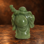 Source-supported rear studio view of the mini green resin Laughing Buddha and shoulder bag