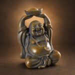 Angled studio view of the miniature stone-colored resin Laughing Buddha on a charcoal-bronze backdrop