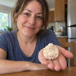Woman holding the 5 cm white miniature Laughing Buddha in her palm at home